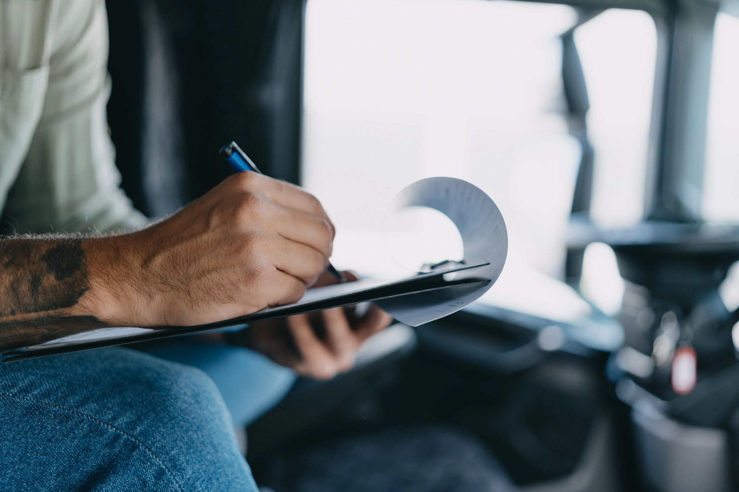 Journalist taking notes on a clipboard inside a vehicle